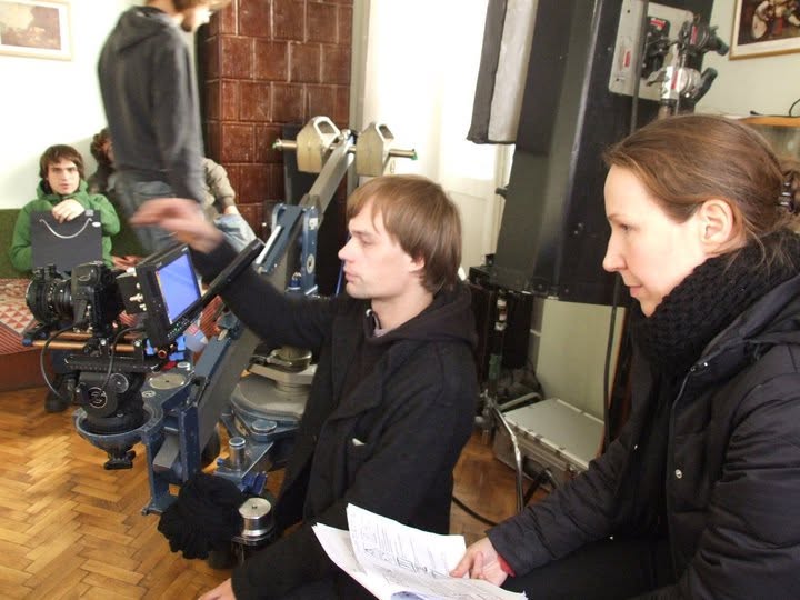 Jurga filmavimo aikštelėje tariasi su operatoriumi prie filmavimo kameros